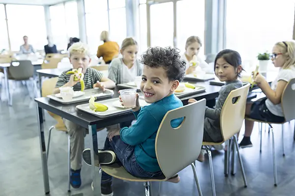 Children eating in a school cafeteria, showcasing the need for reliable commercial kitchen equipment.