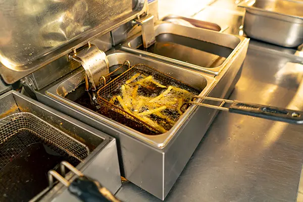 Commercial deep fryer cooking French fries, highlighting the need for reliable restaurant equipment maintenance.