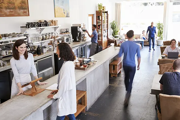 Busy coffee shop with staff serving customers, highlighting the need for efficient commercial appliances.