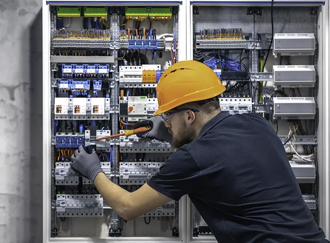 HVAC technician performing electrical maintenance on a commercial refrigeration system for walk-in coolers and freezers.