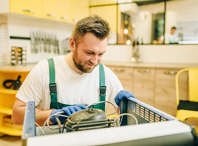 Technician repairing a commercial refrigeration unit as part of San Jose HVAC Guys' appliance repair services.