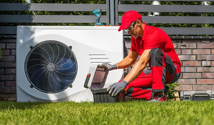 HVAC technician performing repairs on an outdoor air conditioning unit at a residential property.