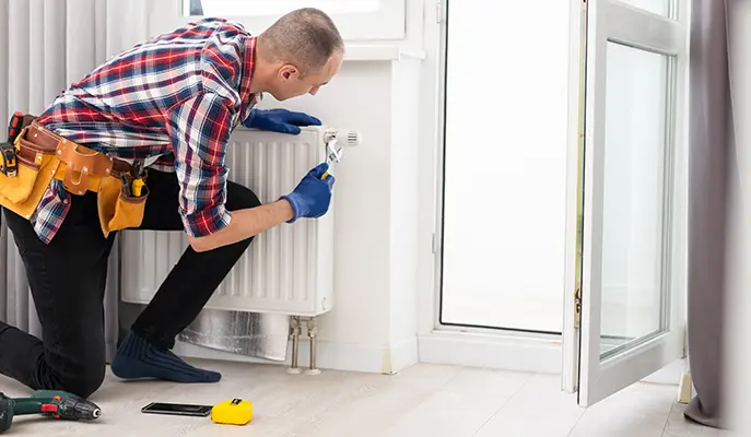 HVAC technician repairing a residential radiator to ensure efficient home heating.